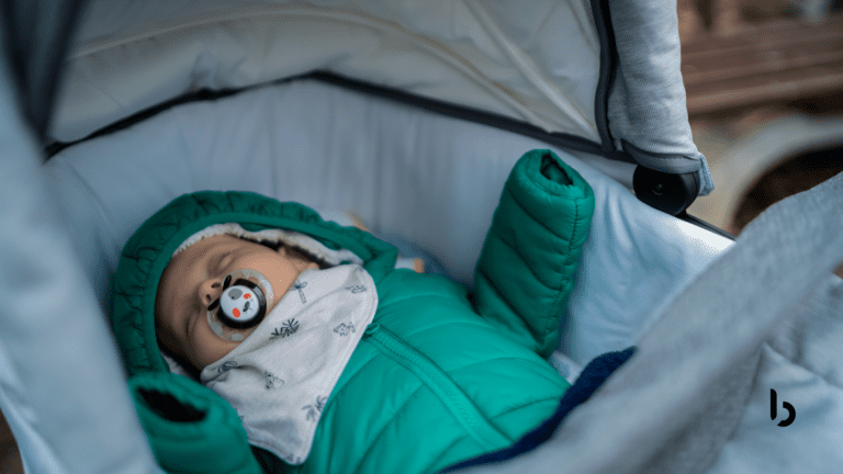 Imagem de um bebê dormindo em um carrinho de bebê, vestido com um casaco verde e chupeta, destacando a tranquilidade e o conforto proporcionados pelo carrinho.